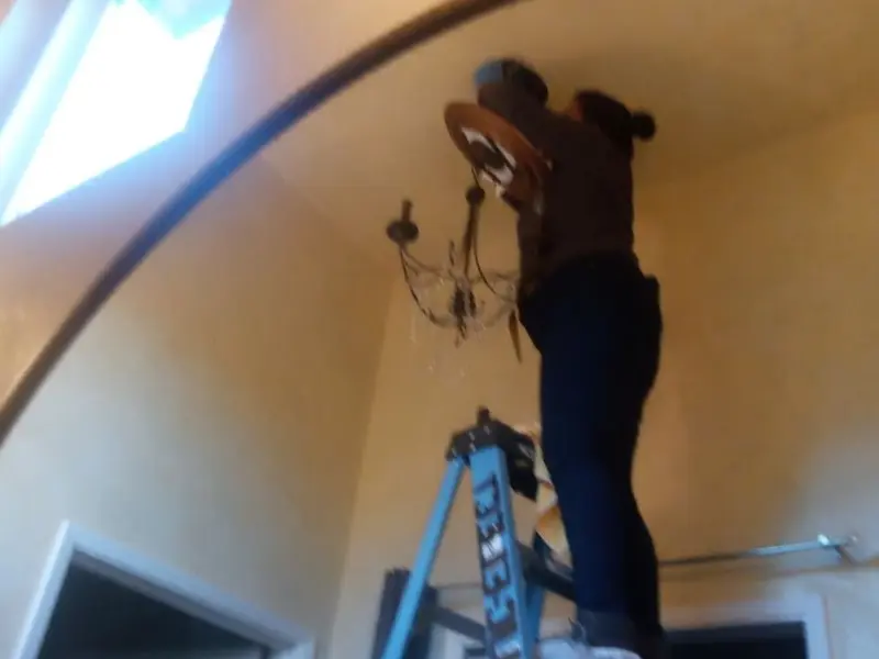 Electrician installing a chandelier in a Pearl residence